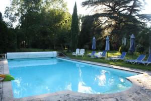 a swimming pool with chairs and umbrellas in a yard at Chateau Castelrives in Bessières