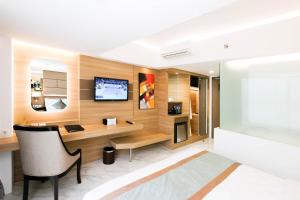 Dream of Aventus Hotel Kuta في كوتا: غرفة معيشة مع مكتب وتلفزيون