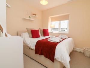 a bedroom with a bed with white sheets and red pillows at Courtyard Cottage in Chittlehampton