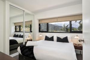 a bedroom with two beds and a large window at Lantern 3 Bedroom Terrace with majestic mountain view in Thredbo