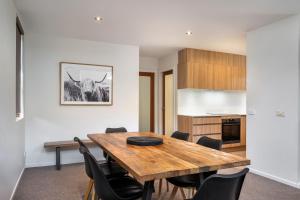 a kitchen and dining room with a wooden table and chairs at Snow Stream 3 Bedroom and loft with gas fire garage parking and balcony in Thredbo
