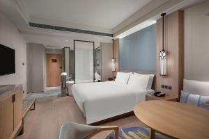 a bedroom with a large white bed and a table at Crowne Plaza Shanghai Nanjing Road by IHG in Shanghai