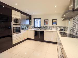 a large kitchen with white cabinets and black appliances at Riverside Park 2 in Keswick
