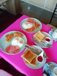 a pink table with plates of breakfast food on it at โรงแรมเมืองเพรียวอินน์ Mueang Phriao Inn Hotel in Sara Buri