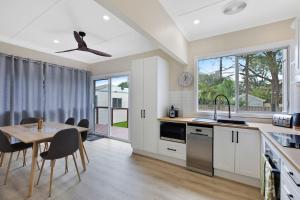 a kitchen with white cabinets and a table and chairs at Cottage Hideaway - Pet Friendly in Budgewoi