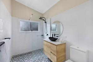 a bathroom with a sink and a mirror at Cottage Hideaway - Pet Friendly in Budgewoi