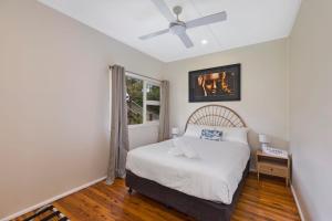 a bedroom with a bed and a ceiling fan at Cottage Hideaway - Pet Friendly in Budgewoi