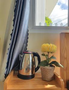 a tea kettle and a plant on a table under a window at Môn Bạc Home in Da Lat