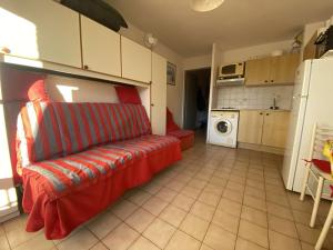 ein Wohnzimmer mit einer roten Couch in der Küche in der Unterkunft Appartement Sainte-Maxime, 1 pièce, 4 personnes - FR-1-226-509 in Sainte-Maxime