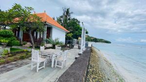 een huis met een tafel en stoelen naast het water bij Juan Beach Bungalow in Nusa Penida
