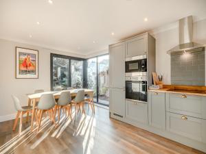 a kitchen with white cabinets and a table and chairs at Beaches in Overstrand
