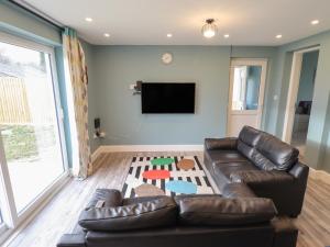 a living room with a leather couch and a flat screen tv at Gordona in Mablethorpe