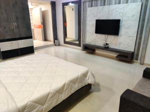 a bedroom with a large bed and a flat screen tv at The Grand Takshak Hotel in Mehsāna +23 photos