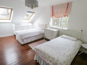a bedroom with two beds and a table and windows at Springwood Cottage in Louisburgh