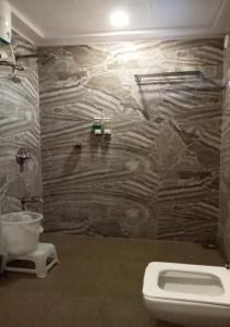 a bathroom with a toilet and a stone wall at The Grand Takshak Hotel in Mehsāna