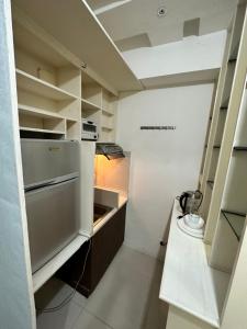 a small kitchen with white cabinets and a refrigerator at Grand Riviera Suits in Manila