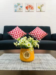 an orange vase with flowers on a table in front of a couch at P1 PineComfyStay Waterpark 7pax Ipoh in Kampong Pinji