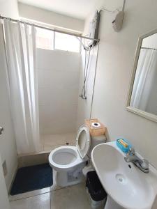 La salle de bains est pourvue de toilettes blanches et d'un lavabo. dans l'établissement CASA CON COCHERA CERCA A LA PLAYA PlMENTEL, à Chiclayo