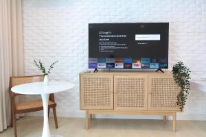 a tv on top of a wooden cabinet with a table at Beachfront Deluxe pool access room one-minute walk to Wonnapha beach in Bangsaen