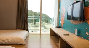 台東市にあるTaitung Railway Innのベッドと大きな窓が備わるホテルルームです。
