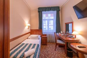 プラハにあるHotel Meteor Plaza Pragueのベッド、デスク、窓が備わるホテルルームです。