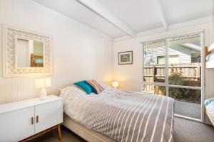 Schlafzimmer mit einem Bett und einem Fenster in der Unterkunft Point Lonsdale Beach House - Relax Beach Surf Golf in Point Lonsdale