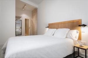 una camera da letto con un grande letto bianco con testiera in legno di Magno Apartments San Gil - Shared Jacuzzi a Siviglia