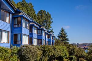 un edificio azul con árboles en el fondo en Hotel Elun, la mejor vista en Frutillar