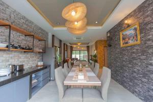 a dining room with a long table and a brick wall at Don Teak Pool Villa Aonang Krabi in Ban Chong Phli
