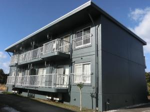 ein schwarzes Gebäude mit Balkonen an der Seite in der Unterkunft Kencha Rumah in Hachijō