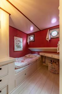 a bedroom with a bed and a red wall at The luxury Boat in Zwolle