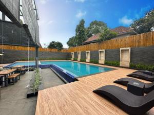 a swimming pool with black chairs and a wooden deck at Yasmin Hotel Karawaci in Tangerang