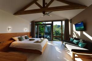 a bedroom with a bed and a couch and a tv at Betikure Parc Lodge in Bourail