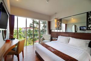 1 dormitorio con cama, escritorio y ventana en The Lerina Hotel Nusa Dua, en Nusa Dua
