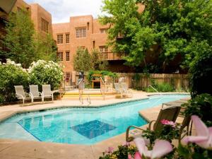 a swimming pool with chairs and a building at The Hacienda & Spa in Santa Fe