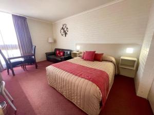 una camera d'albergo con letto e divano di Goulburn Motor Inn a Goulburn