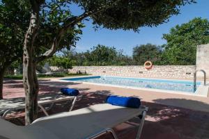 una piscina con un banco y un árbol al lado en Afroditi 4 Villa, en Margarítai