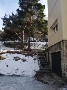 a building with a door and stairs in the snow at Albergue La Pinilla in Madrid