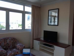uma sala de estar com um sofá e uma televisão e janela em Cityview Serviced Apartment & Hotel Ho Chi Minh City em Cidade de Ho Chi Minh