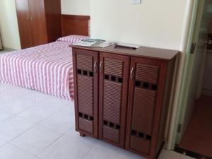 um armário de madeira num quarto com uma cama em Cityview Serviced Apartment & Hotel Ho Chi Minh City em Cidade de Ho Chi Minh