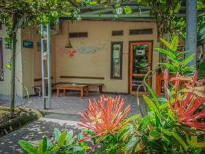 un patio con un banco y flores frente a un edificio en G-Rima Home Stay, en Labuan Bajo