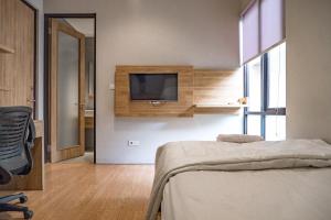 een slaapkamer met een bed en een tv aan de muur bij 3J Living in Binong