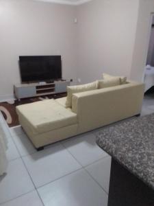 uma sala de estar com um sofá e uma televisão de ecrã plano em Golf view place em Empangeni