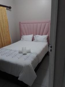 uma cama com uma cabeceira rosa e lençóis e almofadas brancos em Golf view place em Empangeni