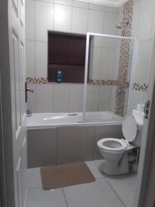 a bathroom with a toilet and a tub and a sink at Golf view place in Empangeni