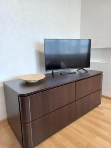 a television on top of a wooden dresser at Maxima apartments in Daugavpils