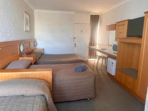 a hotel room with two beds and a desk at Goulburn Motor Inn in Goulburn