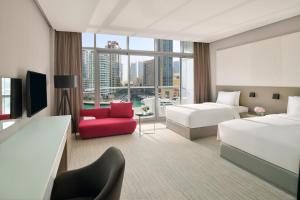 a hotel room with two beds and a red chair at InterContinental Dubai Marina, an IHG Hotel in Dubai