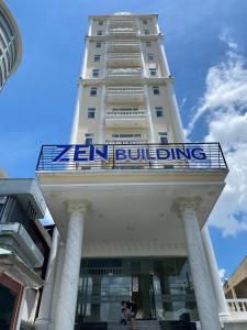 a tall white building with a blue sign on it at ZEN BUILDING in Ho Chi Minh City