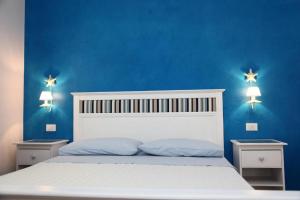 1 dormitorio con 1 cama blanca con paredes azules y 2 mesitas de noche en Bed & Breakfast Venezia, en Marina di Carrara